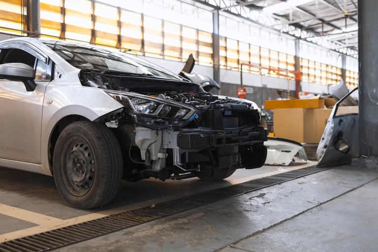 Damaged car in auto repair garage with removed bumper after collision