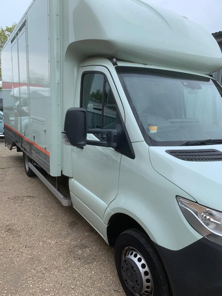 White commercial delivery van with large cargo box parked on gravel lot